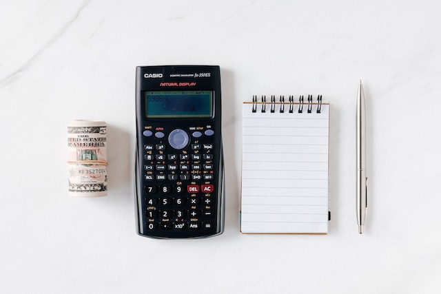 Budget for traveling: Composition of calculator with paper money and notebook with pen.
