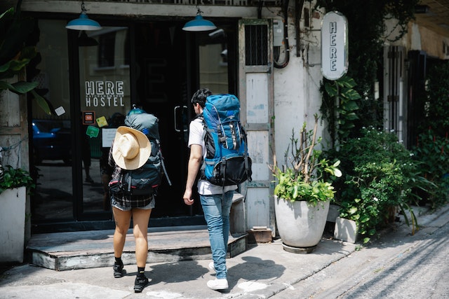 Hostels: couple of travellers with backpacks entering hotel
