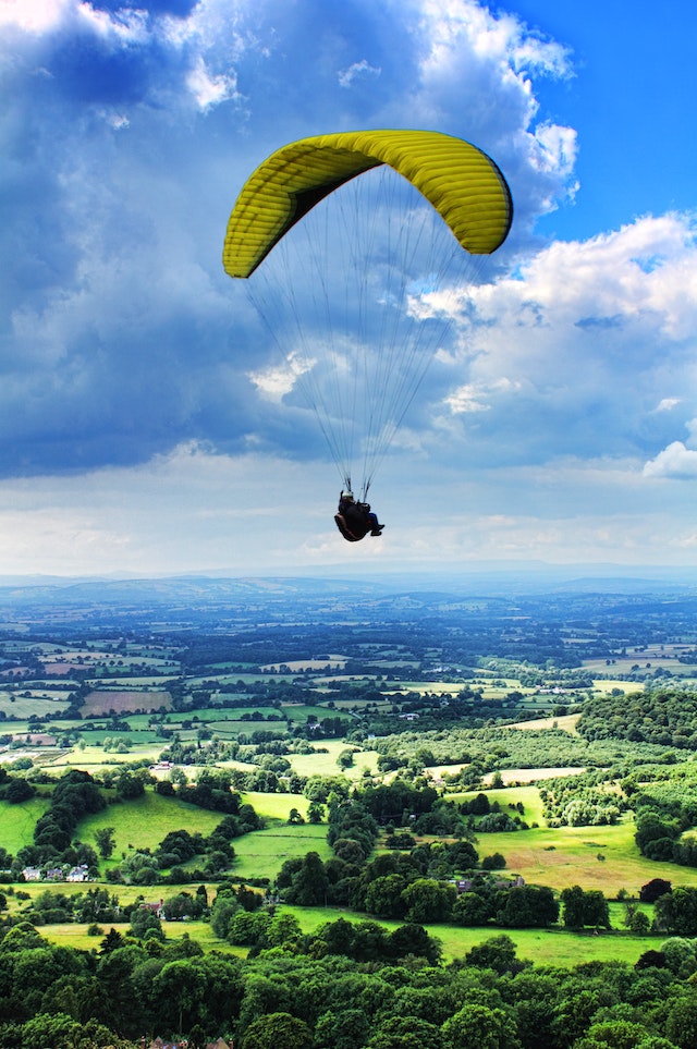 Person Paragliding Under Cloudy Sky.